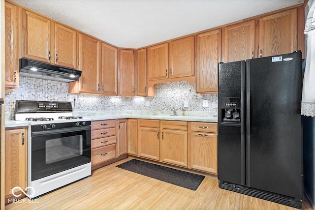 kitchen featuring white gas stove, sink, light hardwood / wood-style floors, decorative backsplash, and black fridge with ice dispenser