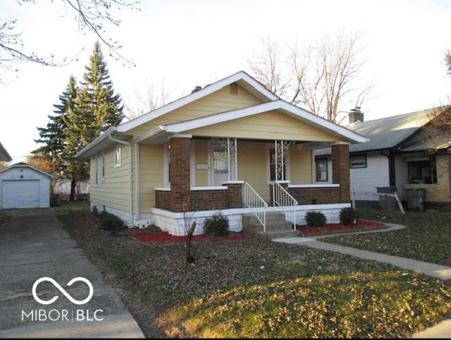 bungalow-style house featuring a porch, an outbuilding, a front yard, and a garage