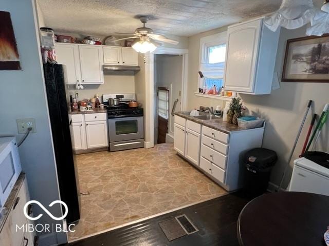 kitchen featuring black refrigerator, a textured ceiling, sink, white cabinets, and stainless steel range with gas stovetop