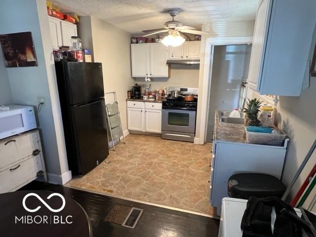 kitchen featuring white cabinets, black refrigerator, ceiling fan, a textured ceiling, and gas stove