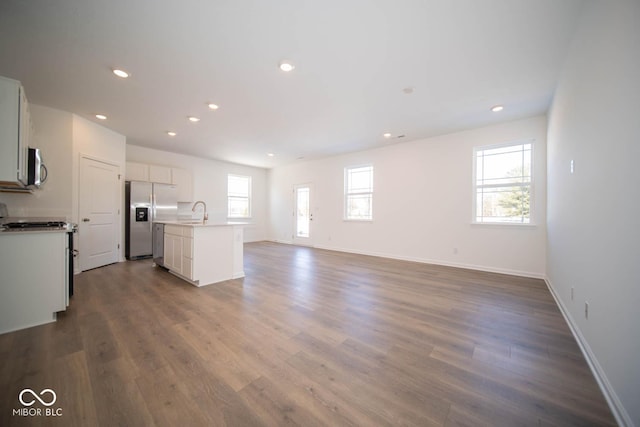 kitchen featuring hardwood / wood-style flooring, white cabinetry, a kitchen island with sink, sink, and stainless steel appliances