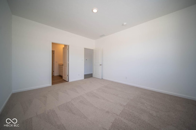 unfurnished bedroom featuring connected bathroom and light carpet