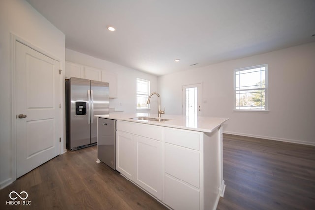 kitchen with dark hardwood / wood-style flooring, sink, appliances with stainless steel finishes, white cabinetry, and an island with sink