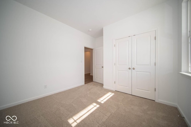 unfurnished bedroom featuring a closet and light carpet