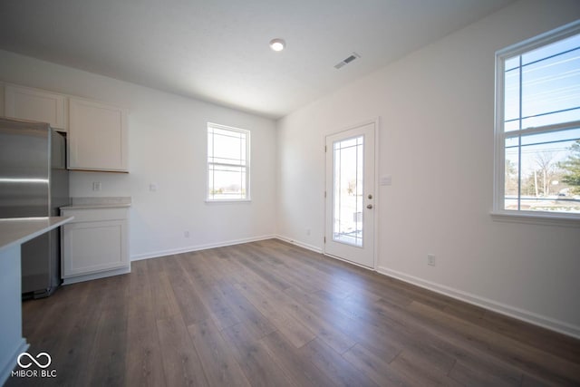 interior space featuring white cabinets, a wealth of natural light, stainless steel refrigerator, and dark hardwood / wood-style floors