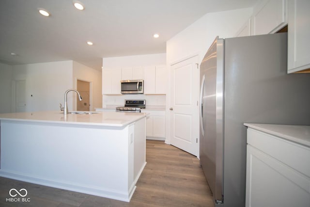 kitchen with sink, white cabinetry, stainless steel appliances, and an island with sink