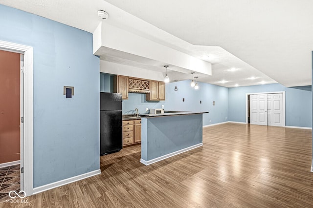 kitchen featuring baseboards, dark wood-style flooring, a sink, and freestanding refrigerator