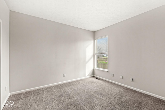 unfurnished room with carpet floors, visible vents, baseboards, and a textured ceiling