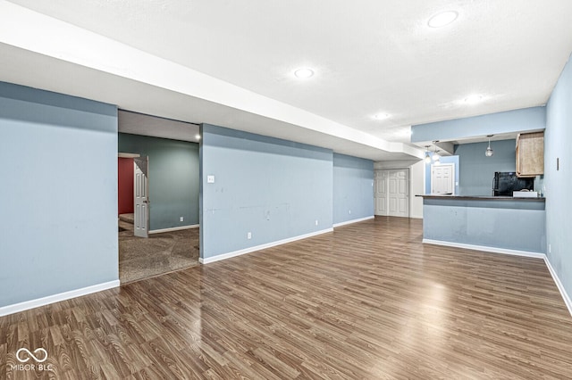 unfurnished living room featuring wood finished floors and baseboards