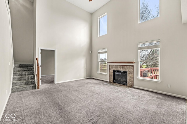 unfurnished living room with stairs, a fireplace, carpet flooring, and baseboards