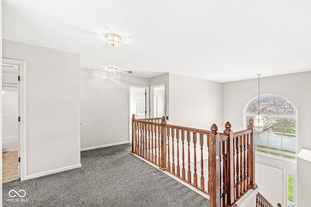 corridor with a notable chandelier, carpet, an upstairs landing, and baseboards