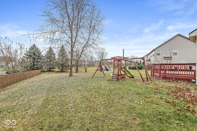 view of yard featuring a deck, a playground, and fence