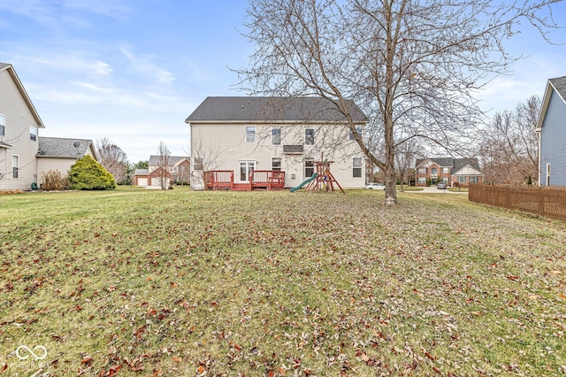 rear view of house with a playground, a yard, a wooden deck, and fence