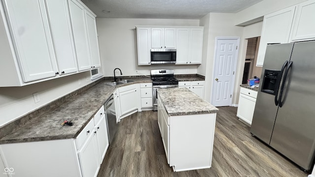 kitchen featuring dark wood-style floors, a kitchen island, stainless steel appliances, and a sink