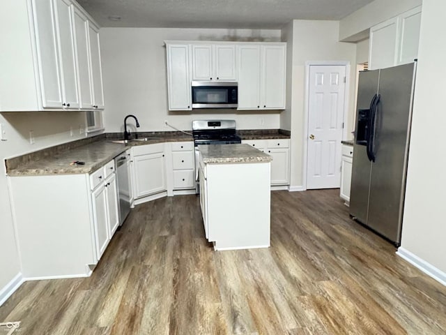 kitchen featuring appliances with stainless steel finishes, dark wood-style flooring, white cabinetry, and a sink