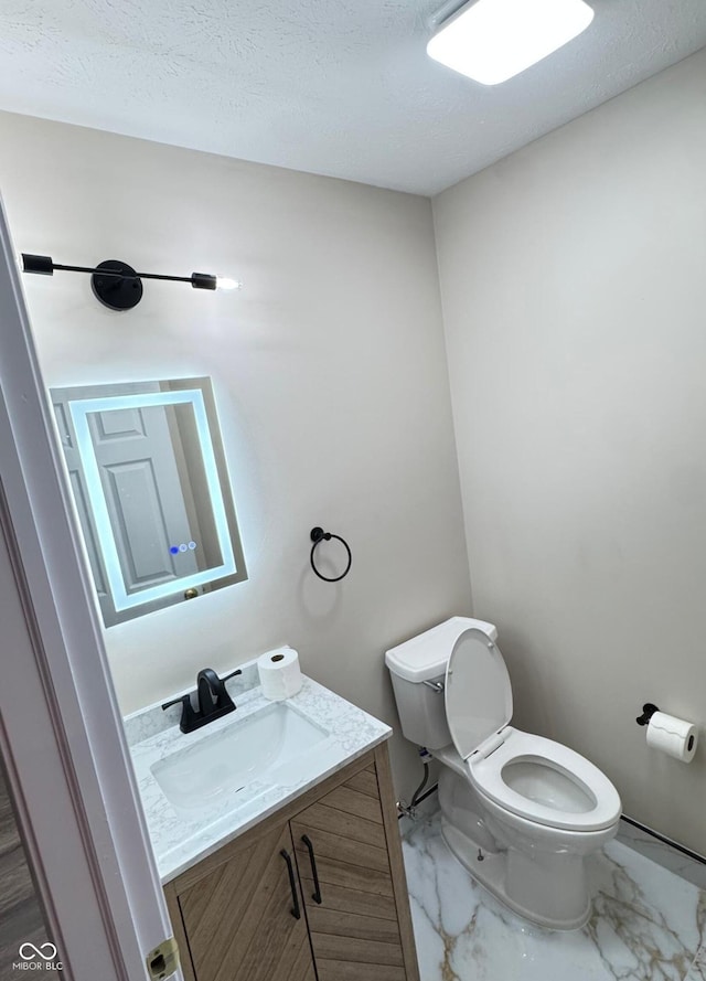 bathroom with a textured ceiling, marble finish floor, vanity, and toilet