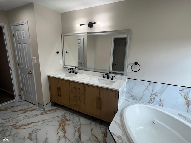 bathroom with a tub with jets, marble finish floor, double vanity, and a sink