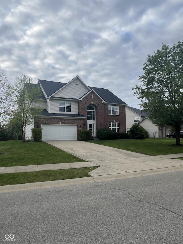 traditional-style house featuring a garage, brick siding, driveway, and a front yard