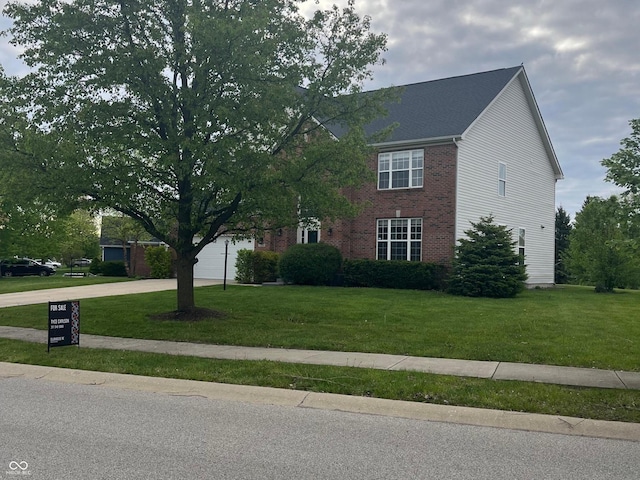 view of front of house with a garage, brick siding, a front yard, and concrete driveway