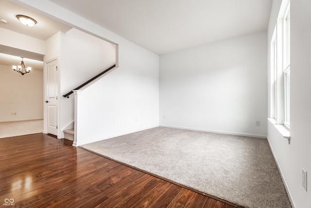 spare room with a notable chandelier and dark hardwood / wood-style flooring