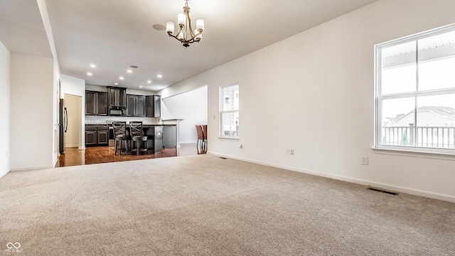 unfurnished living room featuring dark colored carpet and plenty of natural light