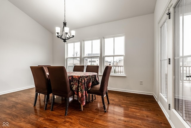 dining room featuring dark hardwood / wood-style flooring, a healthy amount of sunlight, lofted ceiling, and an inviting chandelier