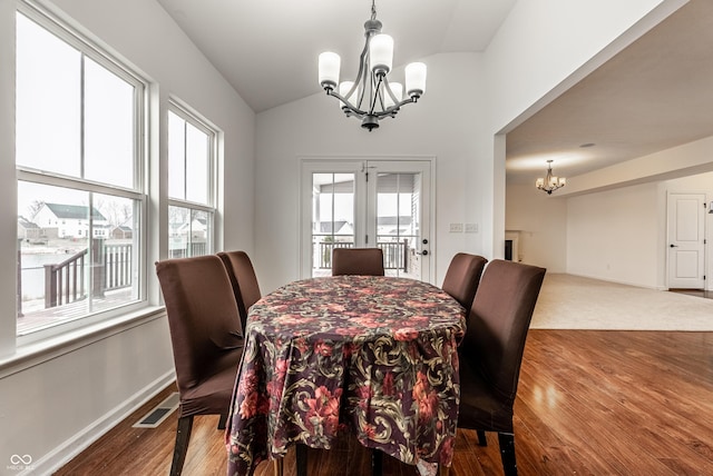 dining room with french doors, wood-type flooring, vaulted ceiling, and a notable chandelier