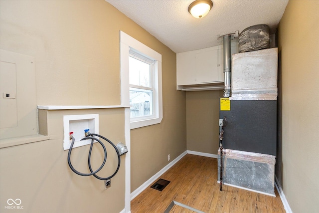 laundry room featuring washer hookup, light wood-type flooring, a textured ceiling, and electric panel