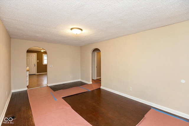 spare room featuring a textured ceiling and dark hardwood / wood-style floors