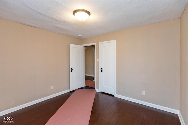 empty room with a textured ceiling and dark hardwood / wood-style flooring