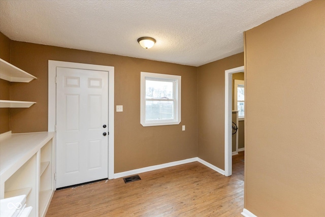 entryway with light hardwood / wood-style flooring and a textured ceiling