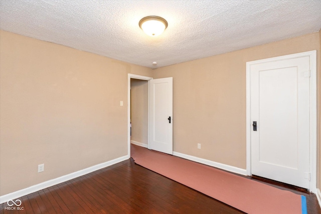 spare room with dark wood-type flooring and a textured ceiling