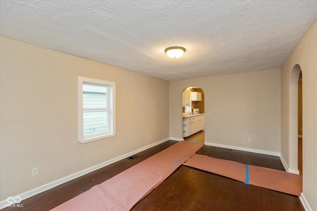 unfurnished room with wood-type flooring and a textured ceiling