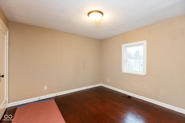 spare room featuring dark hardwood / wood-style floors and a textured ceiling