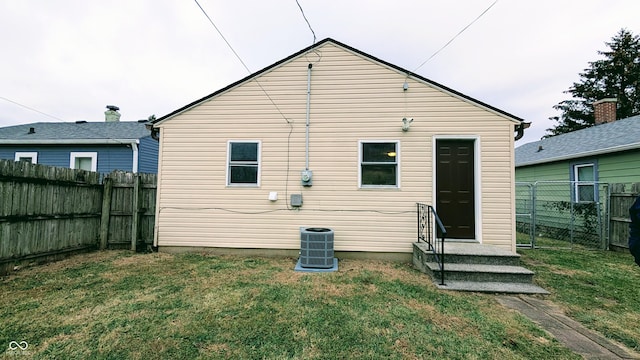 rear view of house with central air condition unit and a yard