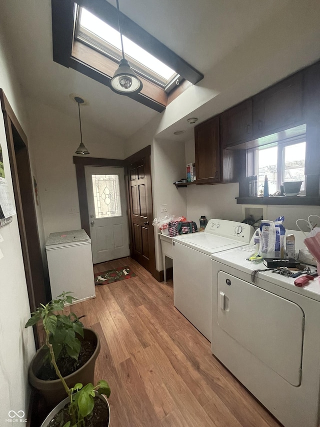 laundry room featuring cabinets, independent washer and dryer, light hardwood / wood-style floors, and a skylight