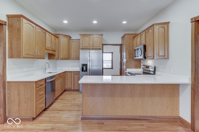 kitchen featuring kitchen peninsula, light brown cabinetry, light wood-type flooring, stainless steel appliances, and sink