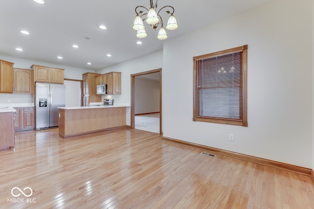 kitchen with decorative light fixtures, light hardwood / wood-style flooring, appliances with stainless steel finishes, and a chandelier