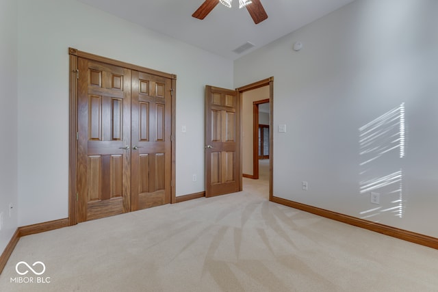 unfurnished bedroom with ceiling fan, light carpet, and a closet