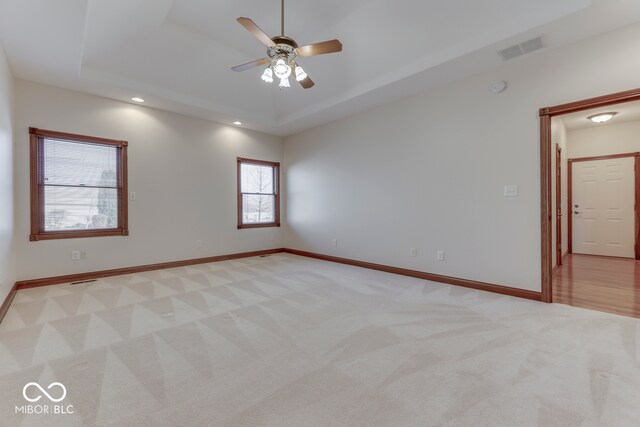 carpeted spare room with ceiling fan and a tray ceiling