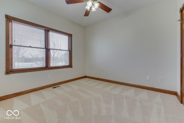 spare room featuring ceiling fan, light colored carpet, and a wealth of natural light