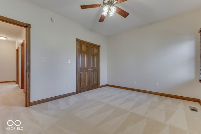 unfurnished bedroom with ceiling fan, light carpet, and a closet