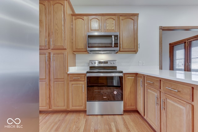 kitchen featuring light brown cabinetry, appliances with stainless steel finishes, and light hardwood / wood-style flooring