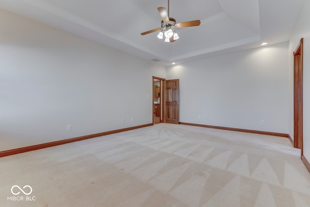 carpeted empty room featuring a tray ceiling and ceiling fan