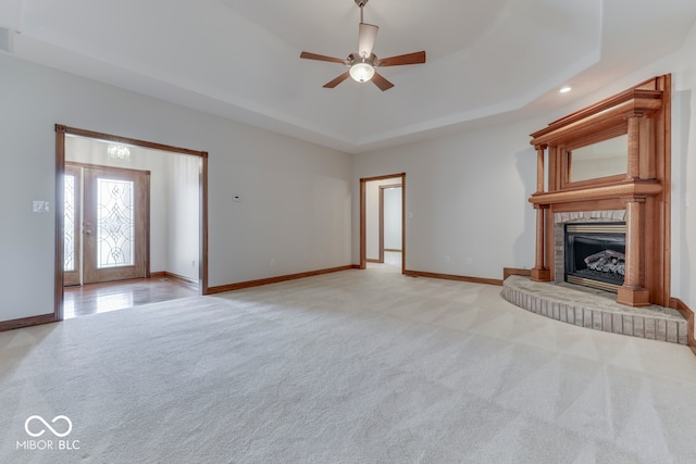 unfurnished living room featuring light colored carpet, a raised ceiling, and ceiling fan