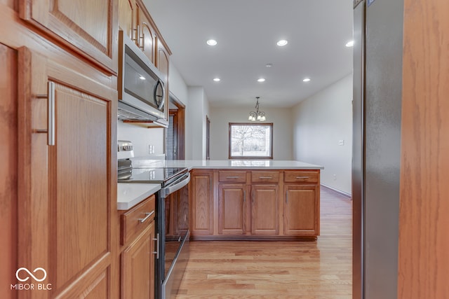 kitchen featuring kitchen peninsula, range with electric cooktop, decorative light fixtures, an inviting chandelier, and light hardwood / wood-style floors