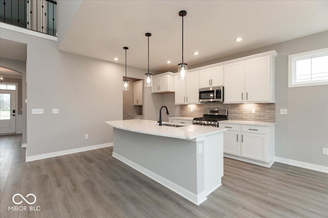 6973 Oakdale Ln, Avon, IN 46123 - kitchen with tasteful backsplash, white cabinets, a sink, light wood-type flooring, and stainless steel appliances