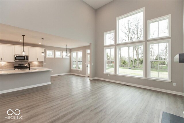 6973 Oakdale Ln, Avon, IN 46123 - unfurnished living room with recessed lighting, a towering ceiling, baseboards, and wood finished floors