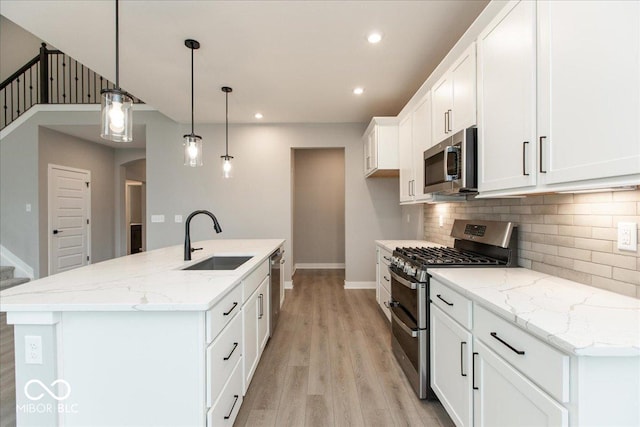 6973 Oakdale Ln, Avon, IN 46123 - kitchen featuring light wood-style floors, tasteful backsplash, white cabinetry, appliances with stainless steel finishes, and a sink