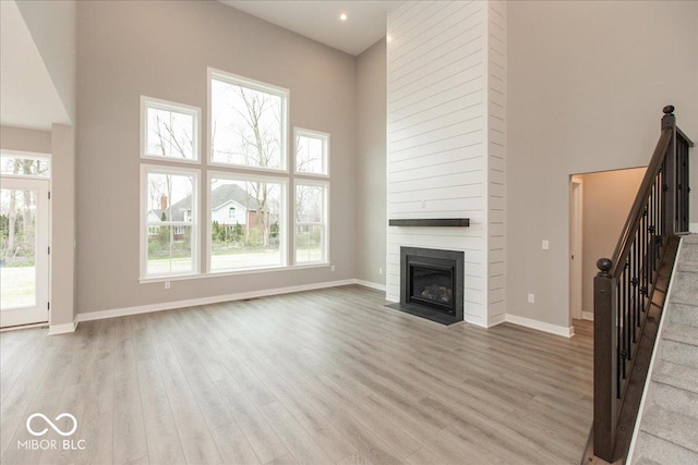 6973 Oakdale Ln, Avon, IN 46123 - unfurnished living room with light wood-style flooring, a high ceiling, baseboards, and a large fireplace